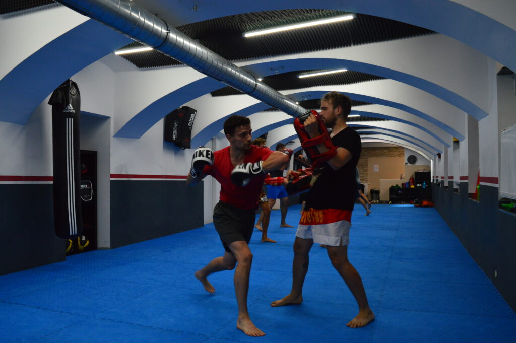 Trainer korrigiert eine Technik im Thaiboxen